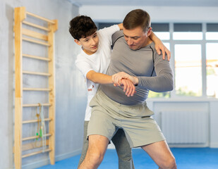 Father teaching his son wrestling or self-defense techniques in the gym
