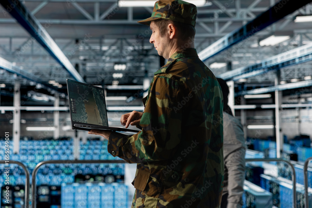 Poster military officer in data center monitoring warfare drone telemetry on laptop dashboard. it specialis