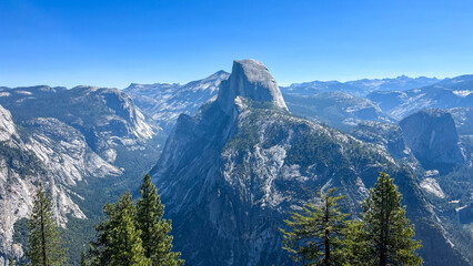mountain landscape with blue sky, view of Yosemite Valley including Half Dome from Glacier Point, in Yosemite National Park in the western Sierra Nevada Mountains of Central California, USA