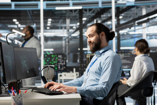 Smiling data center IT professional using artificial intelligence neural networks technology on PC. Happy server farm admin using AI programming language on computer to update hardware