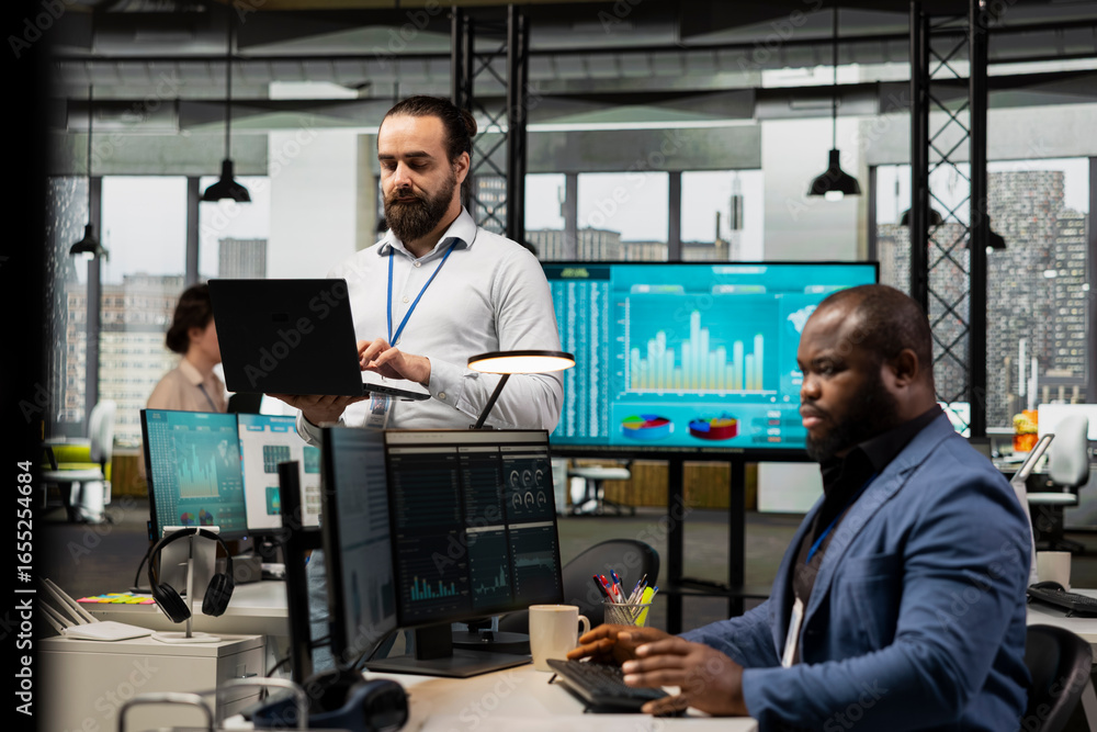 Poster male boss strategizes in a modern workplace surrounded by colleagues, utilizing data charts and grap