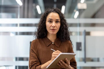 Professional woman taking notes during a business meeting in a modern office