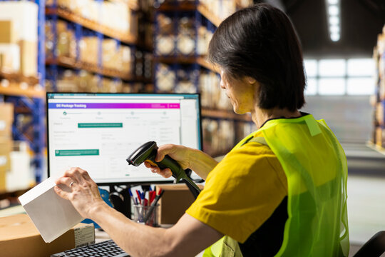 Fulfillment center staff engages in airway bills scanning for order tracking, using scanner on shipping labels in the warehouse. Worker wearing hi vis vest in storage room with shelves.