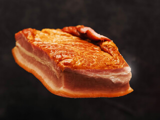 Tasty smoked pork joint in the air, dark color painted background. Fine port meat ham popular in Poland and Baltic states. Premium product, ready to eat.