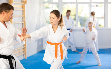 Woman is paired with man teacher to learn how to strike and rehearses blocking opponent, using...