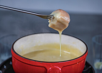 Traditional Swiss cheese fondue in a red pot, dining in Zurich, Switzerland