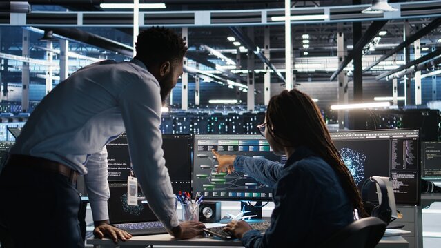 Data center manager supervising engineer using node tree tool to identify equipment performance issues. Server hub team leader talks with IT specialist reviewing data analysis graph, camera A