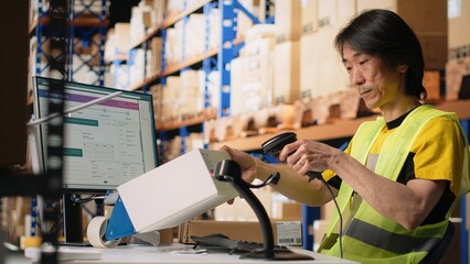Industrial staff member in big fulfillment center scanning tags on boxes, registering shipping...