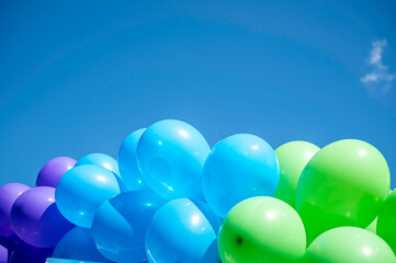 blue and green  balloons against a blue sky with space for copy