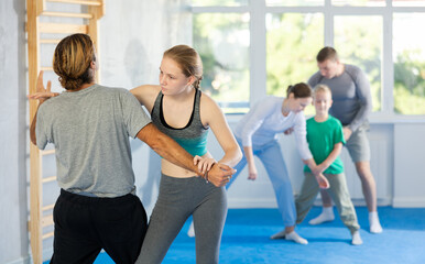 Adolescence girl in gym perform basic elements of krav maga self-defense system, sparring with male teacher. Preparation of athletes before competitions