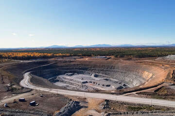 An active gold mining quarry with industrial equipment, view from the edge of the quarry.