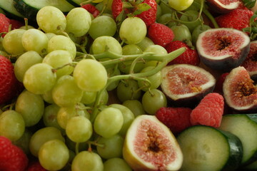 Summer fresh green grapes, strawberries, figs, raspberries, cucumber charcuterie board on wooden platter