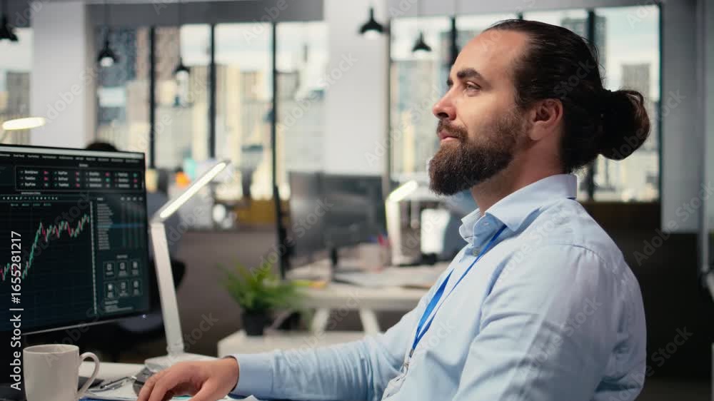 Poster trader in office looking upward with subtle smile on face, visualizing financial independence and fu