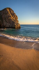 Golden Hour Light Bathes a Coastal Rock Formation and Sandy Beach