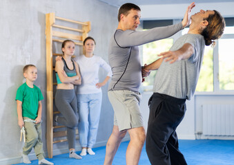 Trainer and man in group self-defense classes practicing sparring technique of blowing to chin in...