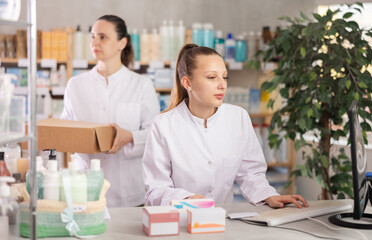 Young woman pharmacist working with computer in pharmacy