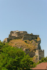 Obraz premium A stunning historic castle rests majestically on a hilltop, surrounded by lush greenery