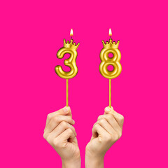 Birthday on a fuchsia background with the number 38 - Hands holding number-shaped candles