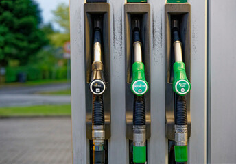 Fuel pumps with diesel black nozzle and green petrol nozzles at gas station © Holger