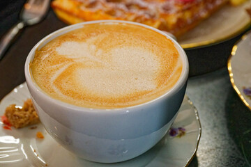 Coffee cup with heart and flower latte art on foam
