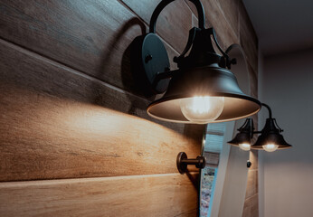wall light fixture next to a round mirror on. wooden wall indoor