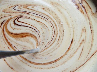 a batter of a chocolate browny mixing with the spoon