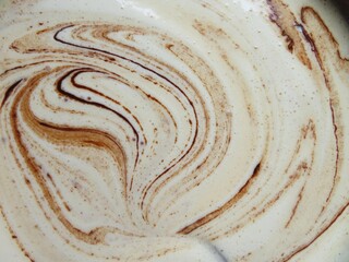 a batter of a chocolate browny mixing with the spoon