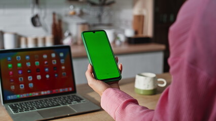 Freelancer hand holding chromakey cellphone working at home kitchen closeup