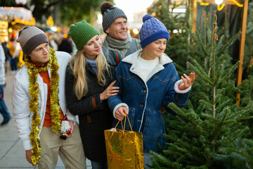 Happy family with two teenagers choose christmas tree at street fair