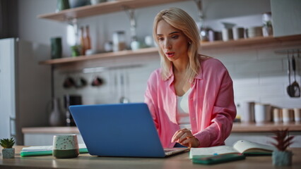 Shocked blonde staring laptop at kitchen closeup. Stressed woman finding mistake