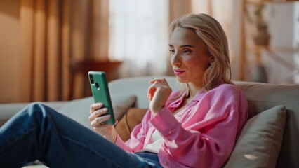 Happy girl sending message by smartphone in apartment closeup. Satisfied woman
