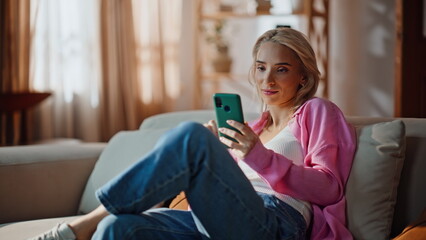 Relaxed girl reading message cellphone at modern apartment closeup. Dreamy woman