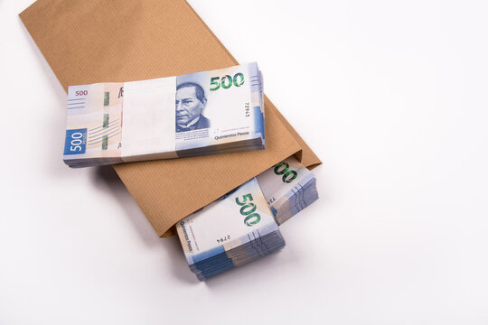 Bolsa de papel llena de billestes mexicanos de 500 pesos, referente a ahorros, soborno o fraude, sobre fondo blanco