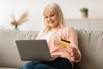 Online Banking And E-commerce Concept. Portrait of smiling senior woman holding credit card and...