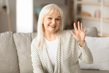 Portrait of cheerful mature woman posing for photo and waving hand to camera, smiling senior lady...