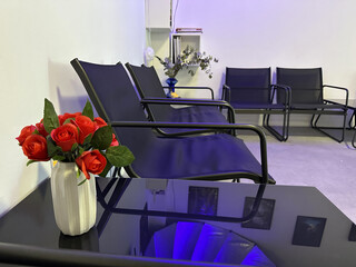 Modern interior design featuring black chairs and a stylish table with a white vase of red roses, creating a welcoming atmosphere in a contemporary space