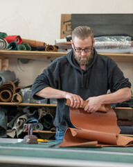 Caucasian bearded man working as a tanner in a workshop. 