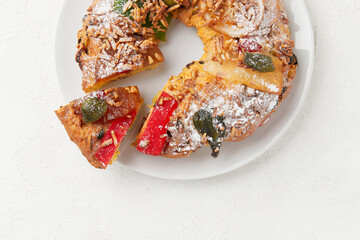 A close up of a slice of a holiday cake with colorful candied fruit and nuts, on a white plate