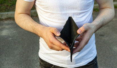 Man’s hands opening a black wallet with nothing inside, poverty and financial difficulty concept.