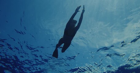 Woman swimming underwater dancing in deep blue crystal clear water 