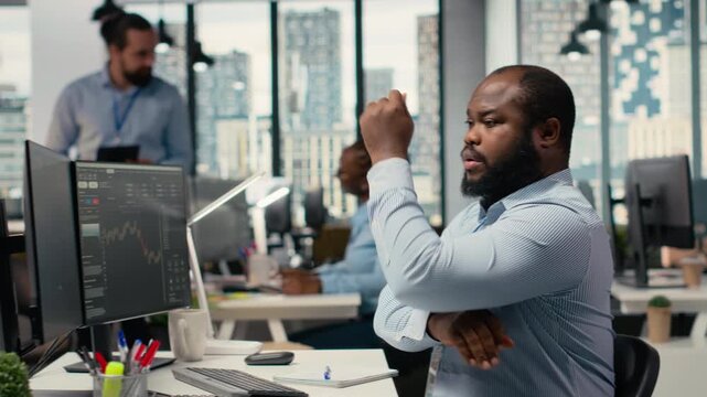 Portfolio manager in prop firm office analyzes stock market trends to enhance investment returns. African american man tracks performance metrics to identify investment opportunities, camera B