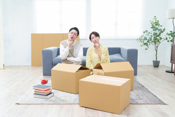 困った表情でダンボールを整理するカップル