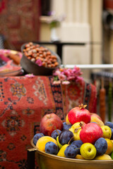 Vertical selective photo. Vegetable counter stall with tasty ripe fresh juicy fruit plate with red pomegranate, plum, yellow apple, pear. Farm street market, harvest autumn fall city holiday Tbilisoba
