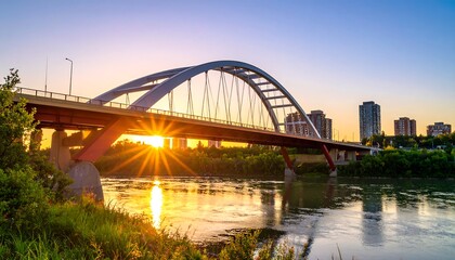 Fototapeta premium Sunrise over a modern arch bridge spanning a river