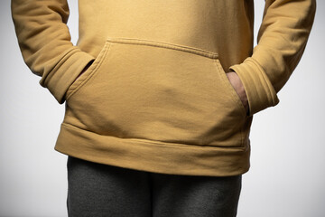 Detail of men's clothing, a yellow sweatshirt on a white background.