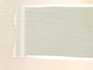 The background is a soft, light wood grain texture. The composition suggests a subtle reveal or layering of materials.