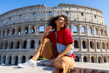 A cheerful and vibrant young woman strikes a pose in front of the iconic Colosseum in Rome, proudly showcasing the stunning beauty and grandeur of this ancient landmark that attracts many tourists