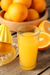 Tasty orange juice, fresh fruits and juicer on wooden table, closeup