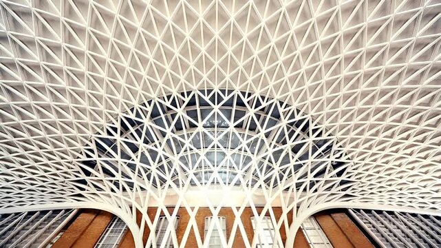 Kings Cross station. London, United Kingdom. Aerial view of a modern architectural structure with a geometrically patterned ceiling. The ceiling is characterized by a series of white.