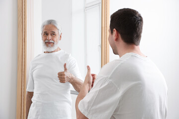 Man seeing himself as elder in mirror. Conceptual collage about past and future, flow of time, age